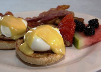 Eggs benedict, bacon and fruit